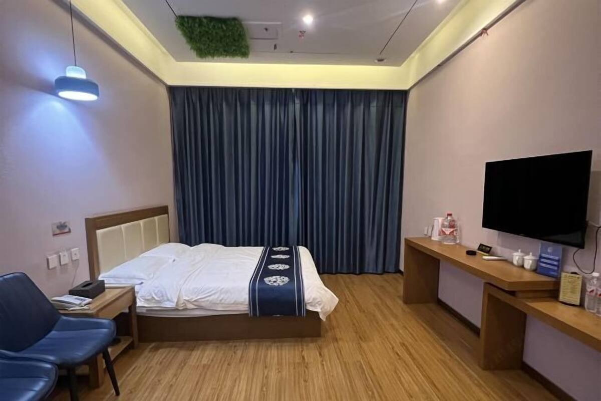 Ein Hotelzimmer mit Bett, Schreibtisch, Stuhl, Fernseher und Holzboden.
