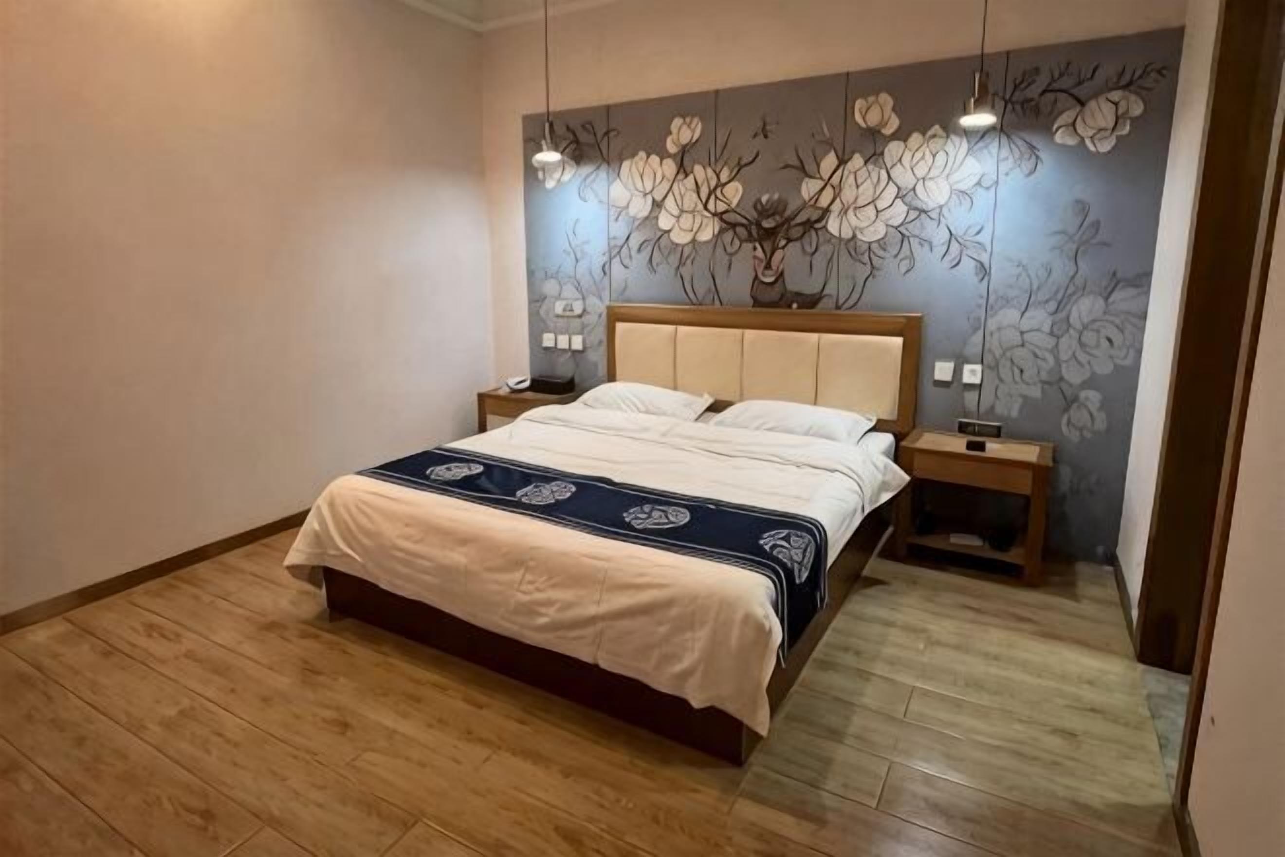 Quarto com cama, mesas de cabeceira, luminária na parede e um mural floral.
