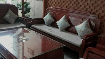 A room with a wooden sofa, a glass coffee table, and a patterned wall.