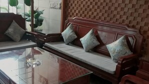 A room with a wooden sofa, a glass coffee table, and a patterned wall. - Naiman Banner Water Yun Tiancheng Hotel (Naiman Banner)