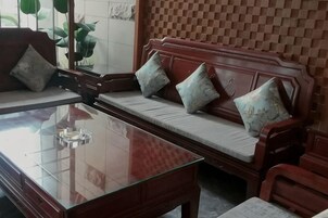 Una habitación con un sofá de madera, una mesa de centro de vidrio y una pared con estampado.