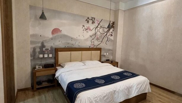 Ein Schlafzimmer mit Bett, Nachttischen, einer Wandmalerei und einer Pendelleuchte.