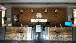 Ein Hotel-Empfangsbereich mit einer Marmor-Theke, Uhren und einem digitalen Bildschirm.
