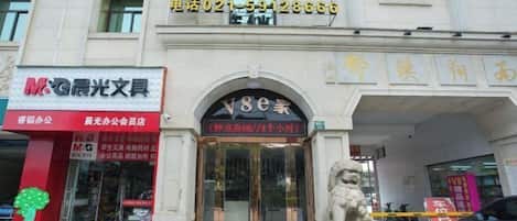 Un bâtiment dont la devanture porte l’inscription « V8连锁宾馆 » et sur laquelle figure un numéro de téléphone.