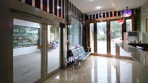 A clean, modern lobby with a glass door entrance, a bench, and a vending machine. - Blue Wave 128 Pulai Hotel (Shanghai)