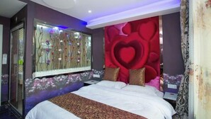 A bedroom with a large bed, a mirror, a red heart-shaped wall design, and a floral wallpaper. - Blue Wave 128 Pulai Hotel (Shanghai)
