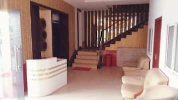 A reception area with a reception desk, a staircase, and a seating area with chairs.