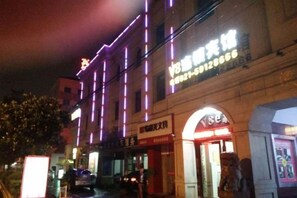 A building with illuminated signage and a storefront. - Blue Wave 128 Pulai Hotel (Shanghai)