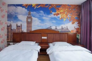 Ein Hotelzimmer mit zwei Betten, einem Stadtbild-Wandgemälde und einem hölzernen Kopfteil.