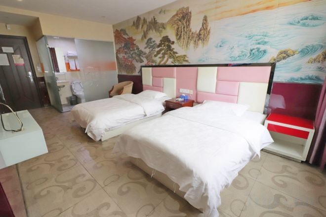 A hotel room with two beds, a desk, and a bathroom.