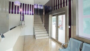 A modern lobby with a marble reception desk, a staircase, and striped walls. - Blue Wave 128 Pulai Hotel (Shanghai)