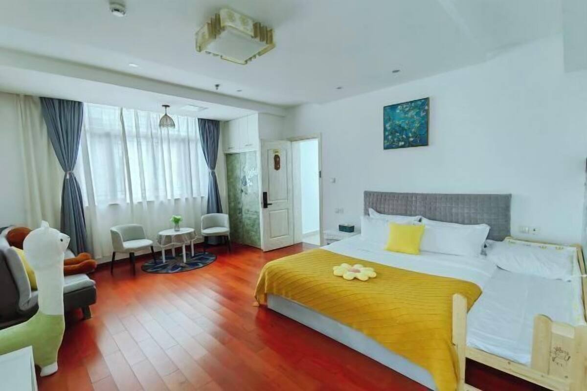 A hotel room with a bed, a desk, a chair, a sofa, and a window with curtains.