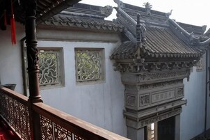 Un edificio tradicional con detalles arquitectónicos ornamentales, incluyendo un tejado de azulejos y marcos de ventanas decorativos.