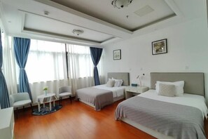 Habitación de hotel con dos camas, una mesita, una silla y un ventanal con cortinas.