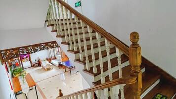 A staircase with wooden balusters and a handrail, leading to a room with a bed, a table, and a chair.