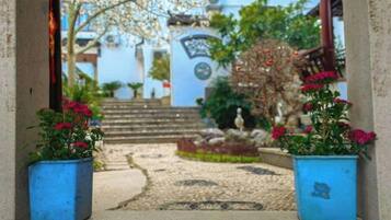 A pathway leading to a building with steps, potted plants, and a sign.