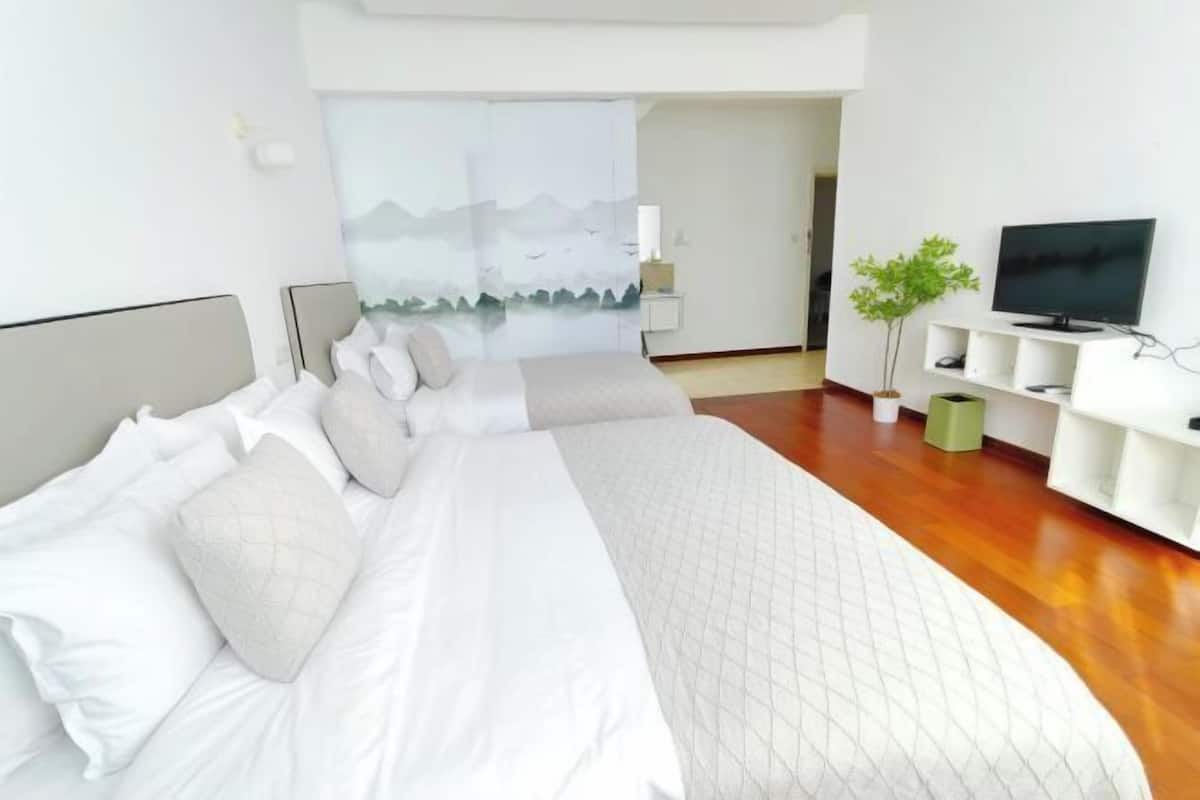 A modern bedroom with a large bed, a television, and a plant.