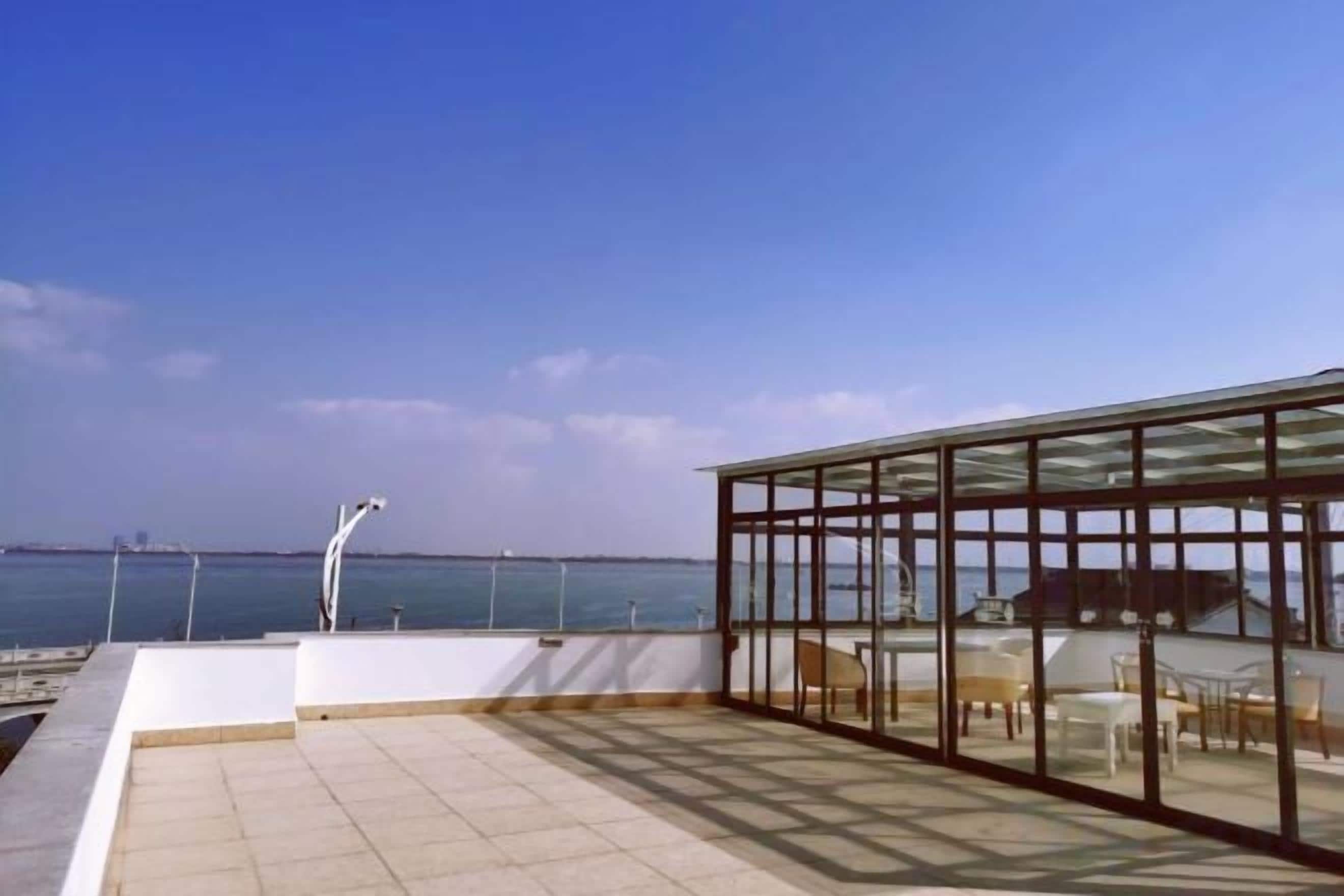 Una terraza en la azotea con cerramiento de vidrio, vistas al mar y un puente a lo lejos.