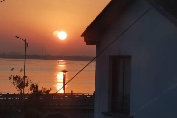 A sunset over a body of water with a bridge and a building in the foreground. - Jiusu Shanshuijian Guesthouse (Suzhou)