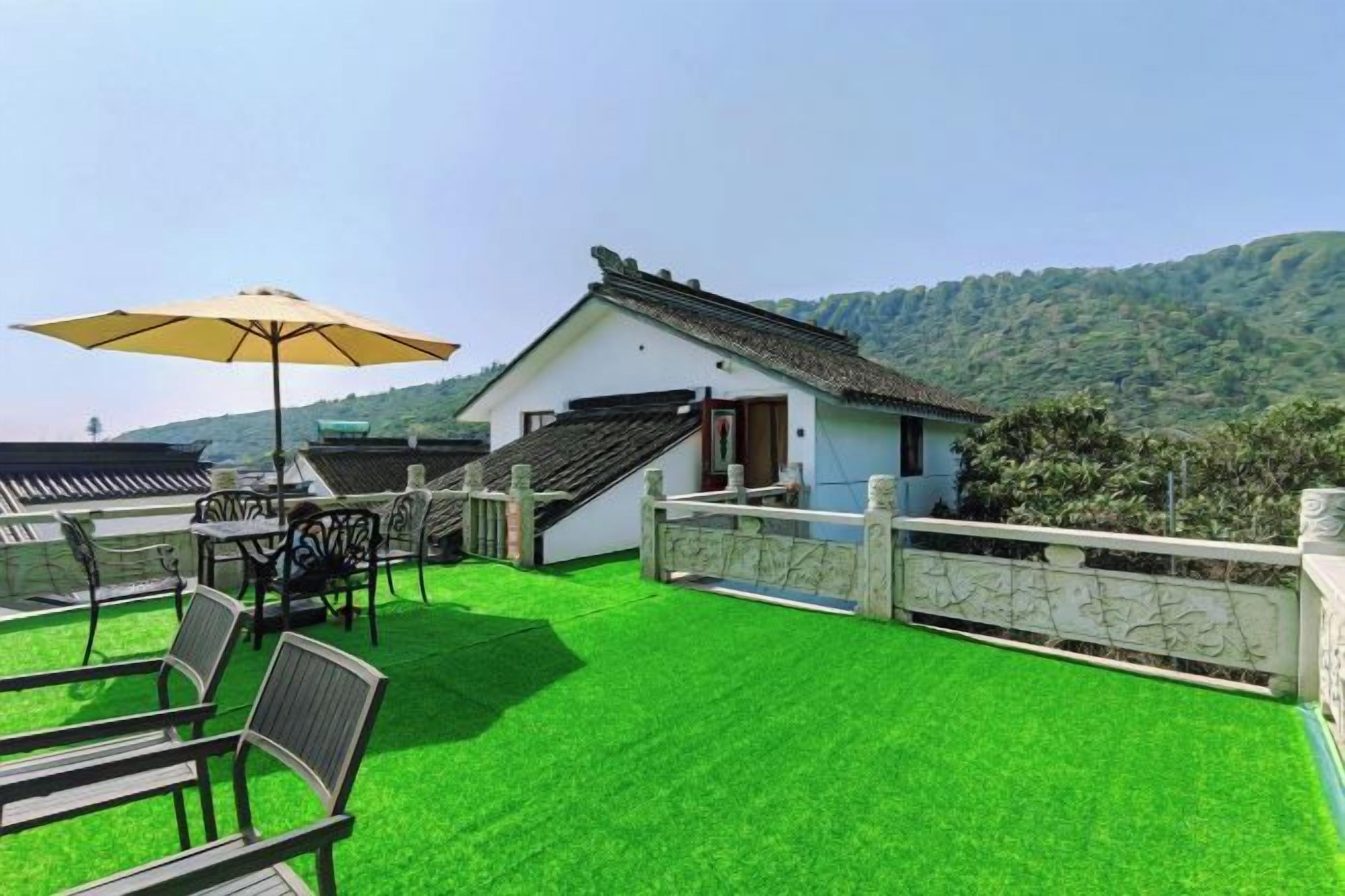 Terraza en la azotea con mesa y sillas, un edificio pequeño y vistas a la montaña.