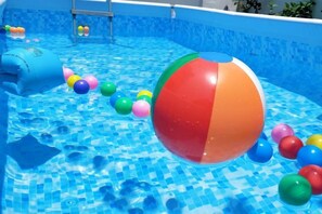 Una piscina con un balón de playa colorido y juguetes flotantes.
