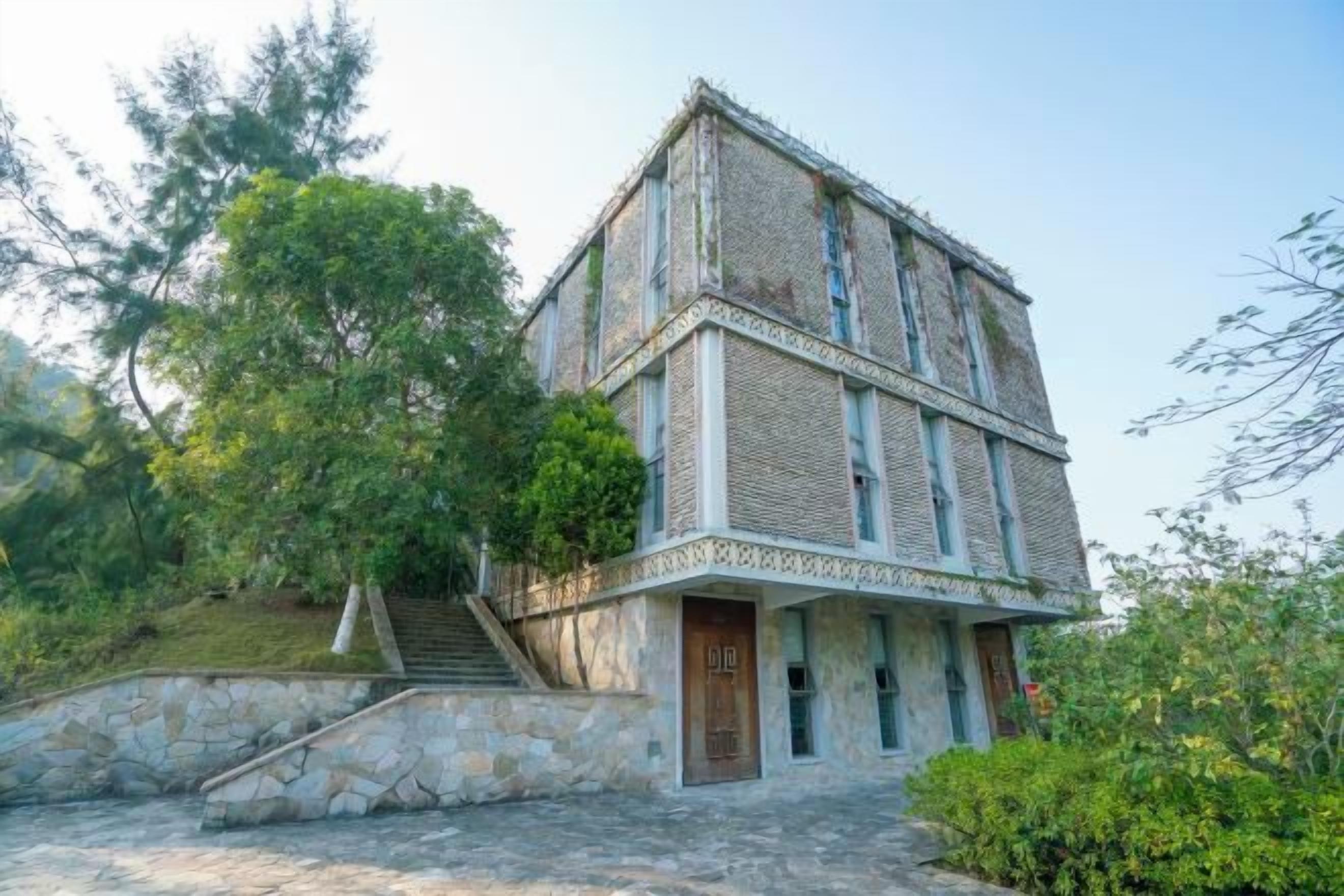 A two-story building with a stone facade, a wooden door, and a staircase leading to the entrance.