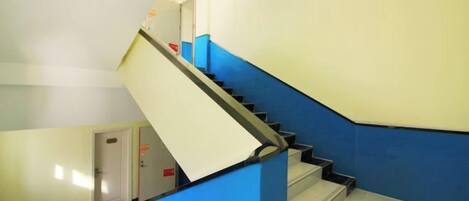 A staircase with a blue handrail and white steps, leading to a door at the bottom.