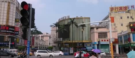 A street scene with a traffic light, vehicles, pedestrians, and commercial buildings.