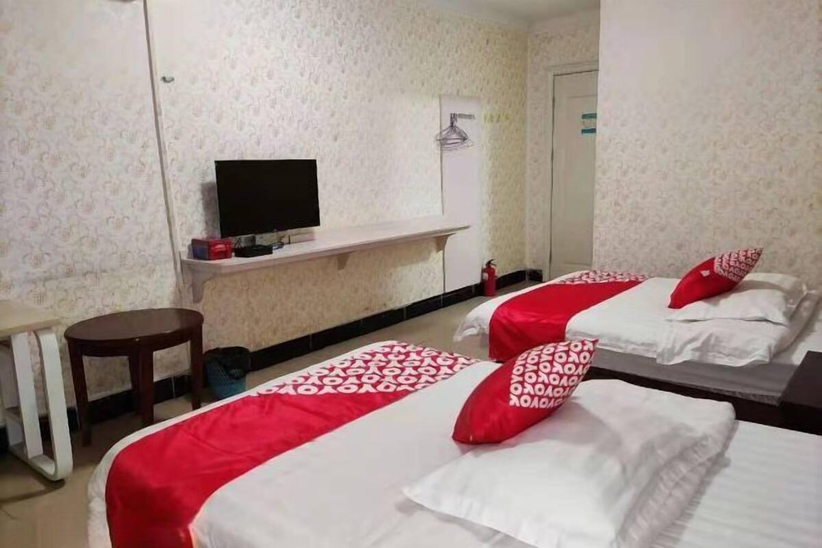 A hotel room with two beds, a TV, a small table, and a mirror.