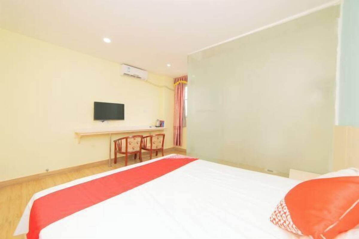 A hotel room with a bed, a desk, a chair, and a television.
