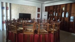 A dining area with multiple wooden chairs and a red tablecloth. There is a television on the wall and a refrigerator in the background. - Jing County Zhenshan Mountain Villa (Jing County)