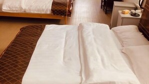 A hotel room with two beds, a desk with a lamp, and a small table with a coffee maker. - Feiyu Hostel (Shanghai)