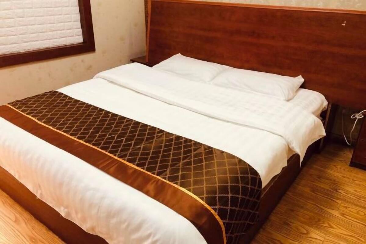A neatly made bed with a patterned bedspread and a wooden headboard.