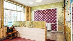 A reception area with a wooden counter, a water dispenser, and a patterned wall. - Feiyu Hostel (Shanghai)