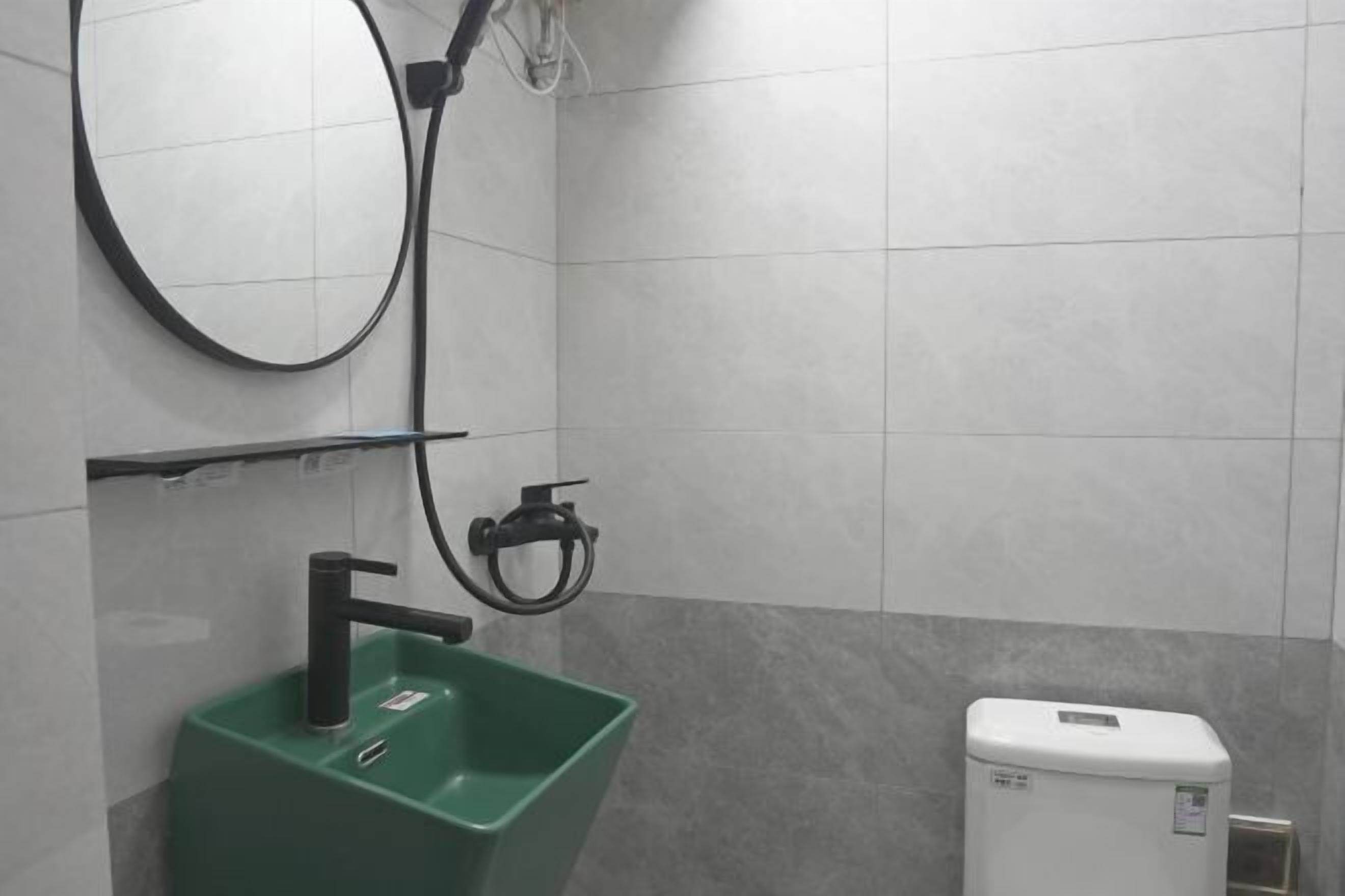 A bathroom with a green sink, a mirror, and a white toilet.