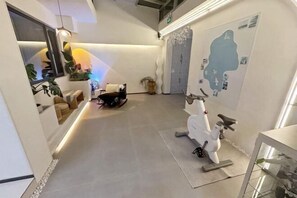 A hallway with a seating area, a white exercise bike, and a wall with a map. - Long Island Fusheng Qingcheng Holiday Homestay (Yantai)