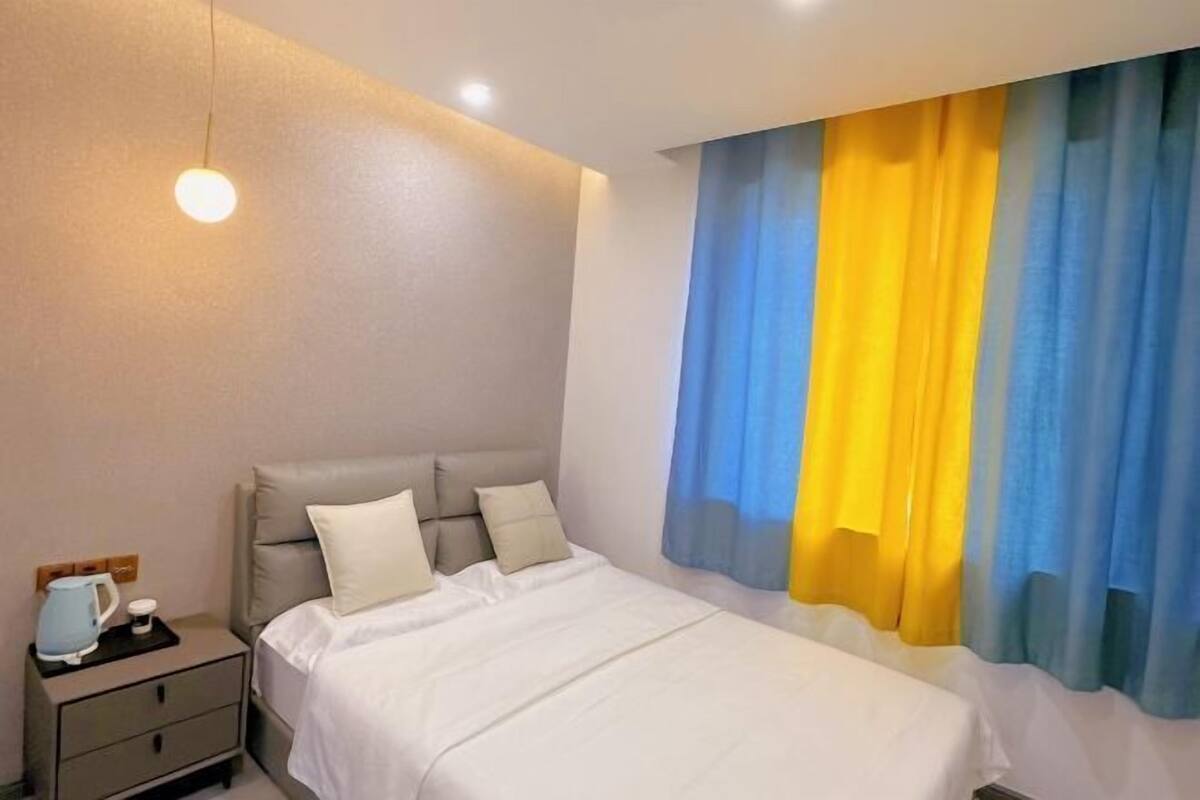 A hotel room with a bed, bedside table, and curtains.