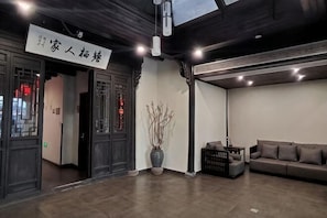 A hotel lobby with a reception desk, a sofa, a large vase, and a sign.