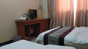 Habitación de hotel con dos camas, un escritorio y televisor, además de una cortina.