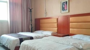 Habitación de hotel con dos camas, cabecera de madera, un cuadro en la pared y una ventana con cortinas.