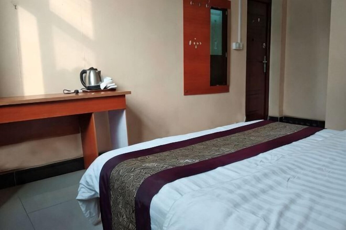 Una habitación de hotel con una cama, un escritorio de madera, un teléfono y un espejo.