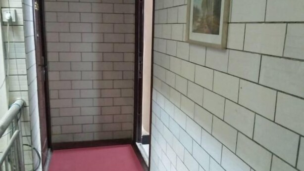 Un pasillo estrecho con alfombra roja, paredes de azulejos blancos y una barandilla de metal a un lado.