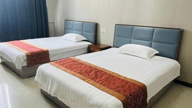 Two single beds with headboards, a nightstand, and a window with curtains. - Minnan Lingang Mingdu Hotel (Junan County)