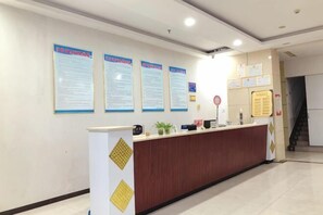 A reception desk with informational posters, a counter, and a staircase in the background. - Minnan Lingang Mingdu Hotel (Junan County)