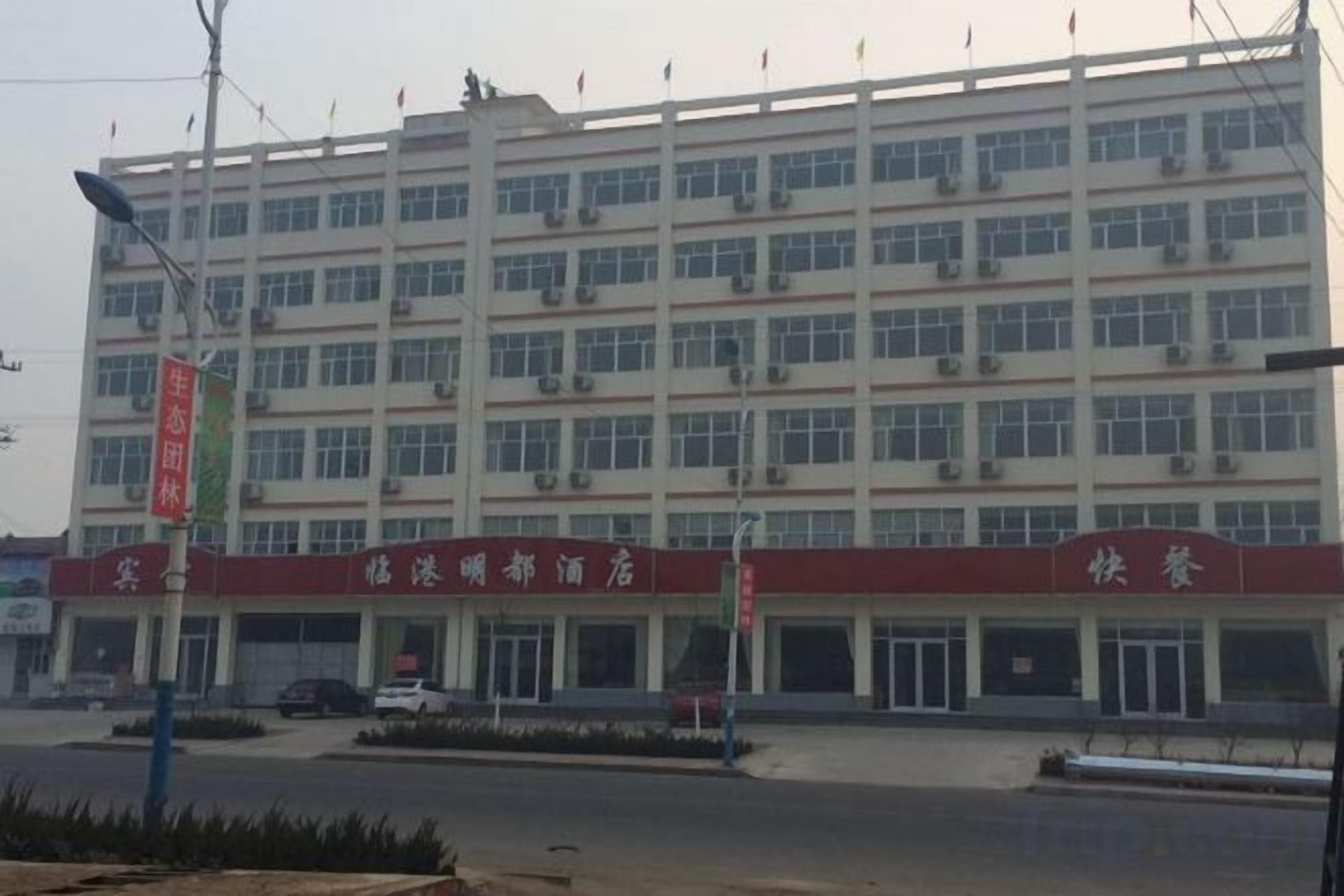 A multi-story building with a red and white facade, multiple windows, and a signboard.