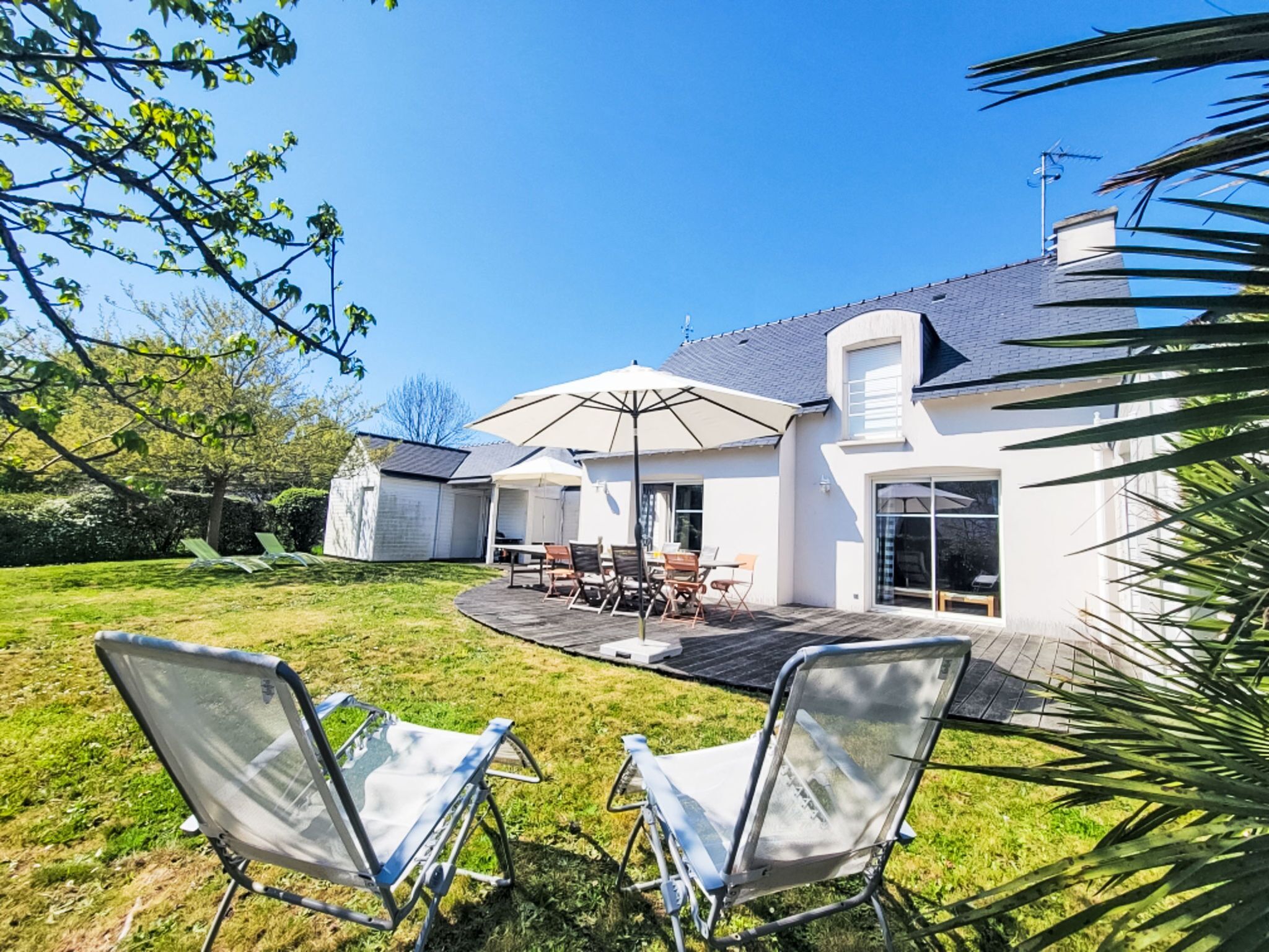Una casa con patio, mobiliario exterior y jardín.
