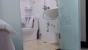Un baño con inodoro, lavamanos y zona de ducha.