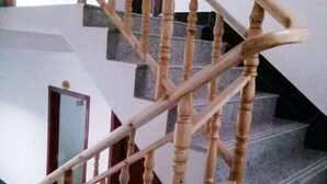 Una escalera con balaustres de madera y barandilla, que lleva a un rellano con una puerta.