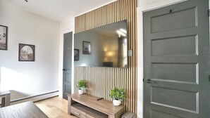 A modern living room with a large mirror, wooden panel wall, and a door.