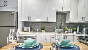 A modern kitchen with white cabinets, a stainless steel refrigerator, a toaster, and a coffee maker.
